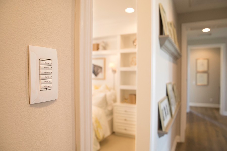 A Control4 lighting keypad on the wall outside of a bedroom. The home is well-lit and inviting.