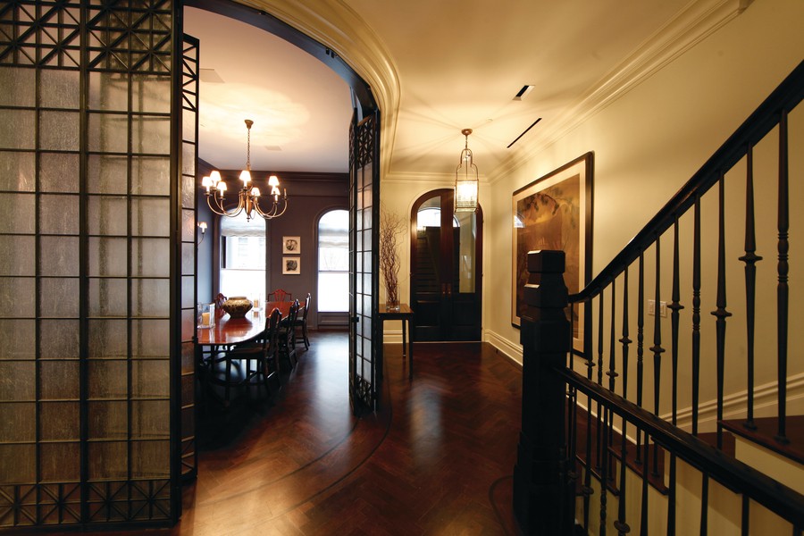 A warmly-lit foyer with stairs and a sliding door entryway to a dining room.