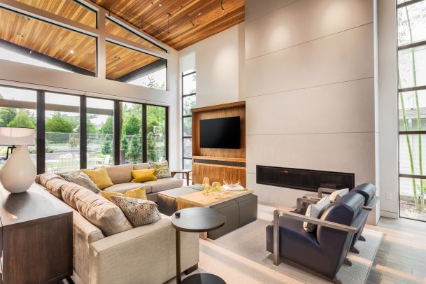 Living room with large windows, wooden ceilings, and tv on wall