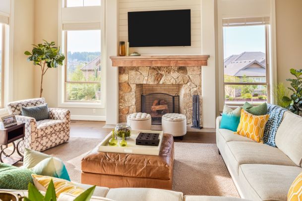 Living room with large windows, stone fireplace and tv on wall