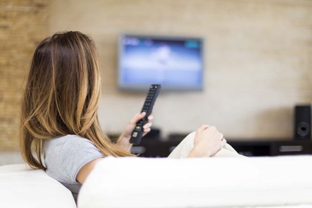 Woman holding remote looking at tv